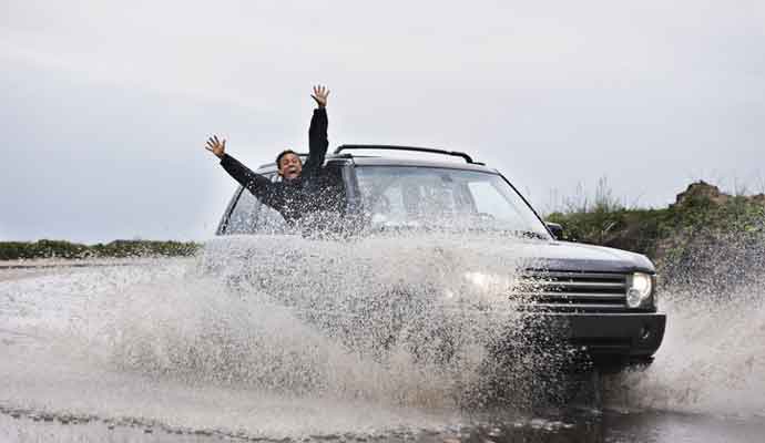 Man leaning out of splashing car