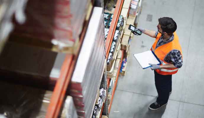 Worker with scanner making review of goods in warehouse